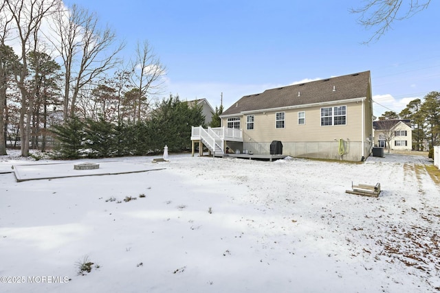 snow covered rear of property with a deck