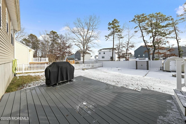 snow covered deck featuring a shed and grilling area