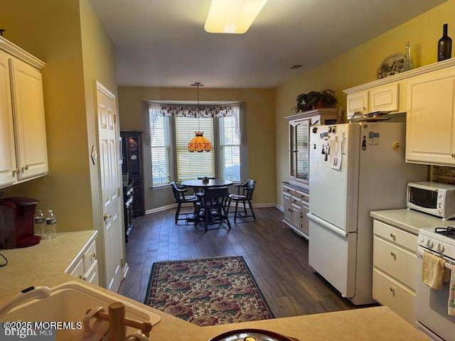 kitchen featuring pendant lighting, white cabinetry, white appliances, and dark hardwood / wood-style flooring