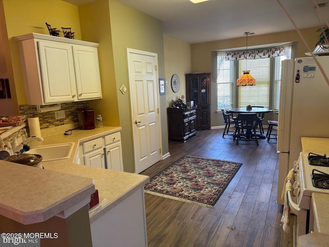 kitchen featuring dark wood-type flooring, sink, kitchen peninsula, white appliances, and white cabinets