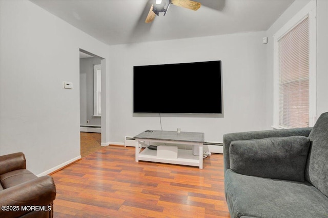 living room featuring a baseboard heating unit, hardwood / wood-style floors, and ceiling fan