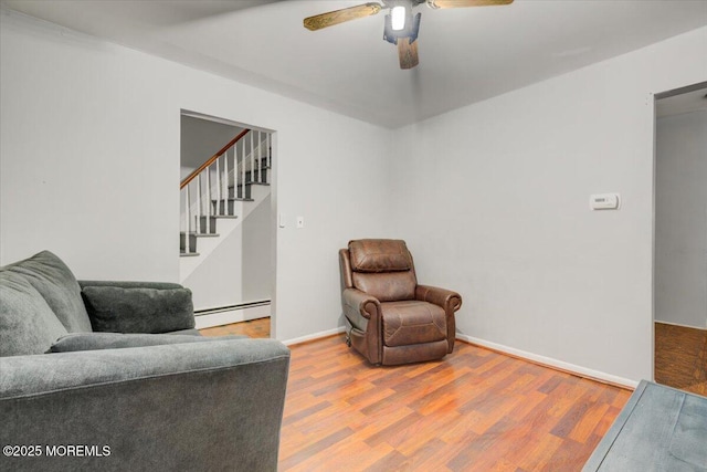 living area with wood-type flooring, ceiling fan, and baseboard heating