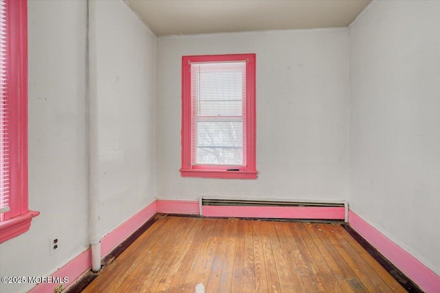 unfurnished room with a baseboard heating unit and hardwood / wood-style floors