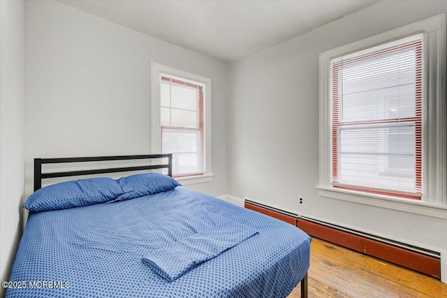 bedroom featuring baseboard heating and wood-type flooring