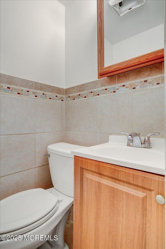 bathroom with vanity, tile walls, and toilet