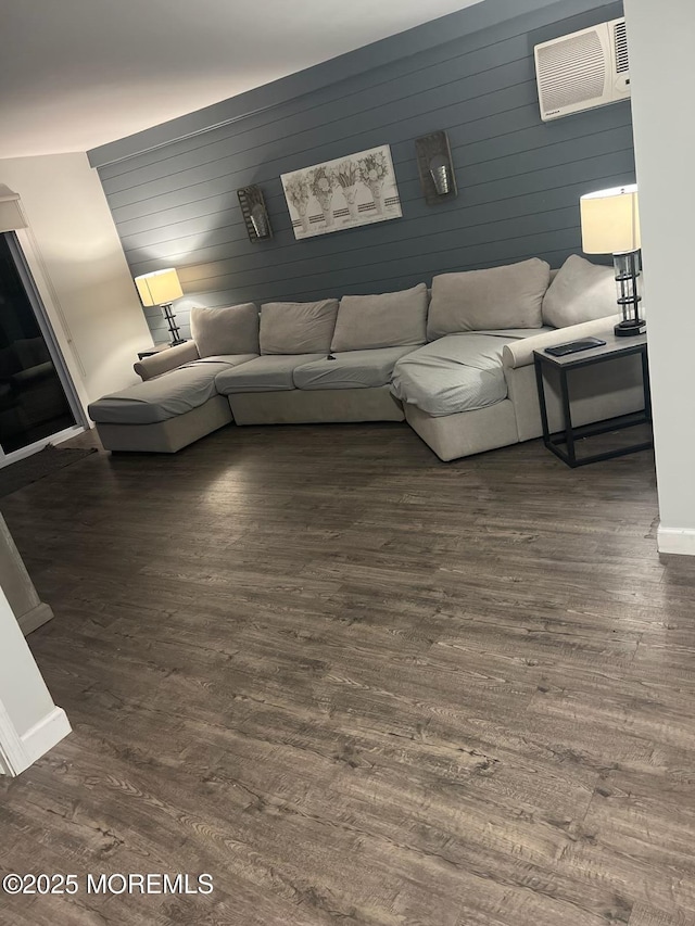 living room featuring dark hardwood / wood-style floors, a wall mounted air conditioner, and wooden walls