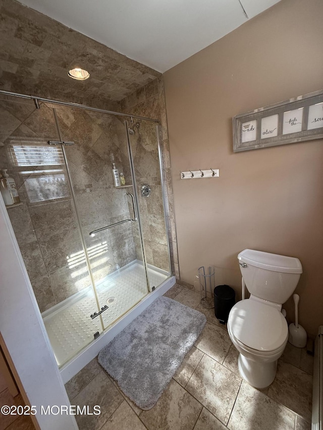 bathroom featuring a shower with shower door and toilet