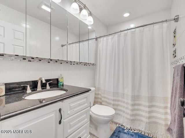 bathroom with tile walls, vanity, and toilet