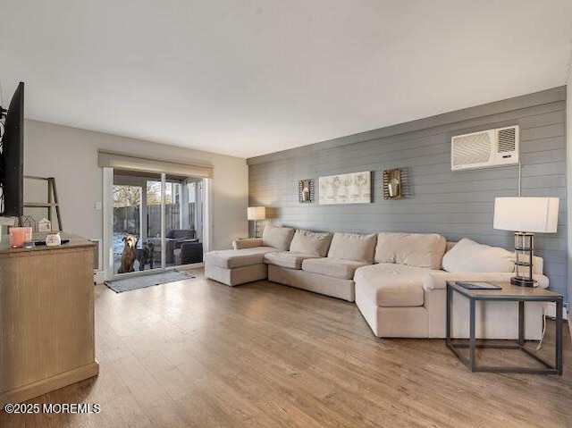 living room with a wall mounted air conditioner and hardwood / wood-style floors