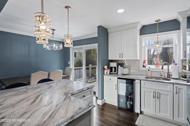 kitchen with wine cooler, sink, white cabinetry, pendant lighting, and light stone countertops