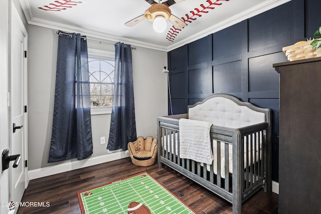 bedroom featuring crown molding, a nursery area, ceiling fan, and dark hardwood / wood-style flooring