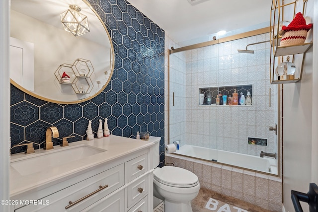 full bathroom featuring tile walls, bath / shower combo with glass door, vanity, decorative backsplash, and toilet