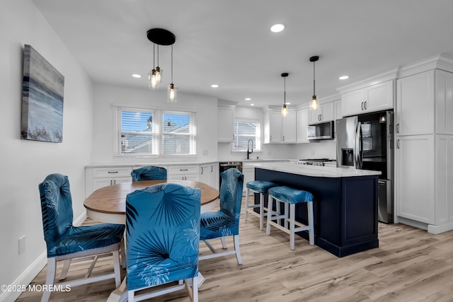 kitchen with light wood finished floors, a kitchen island, white cabinetry, and stainless steel appliances