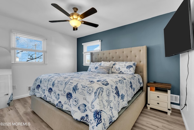 bedroom featuring ceiling fan, wood finished floors, visible vents, and baseboards