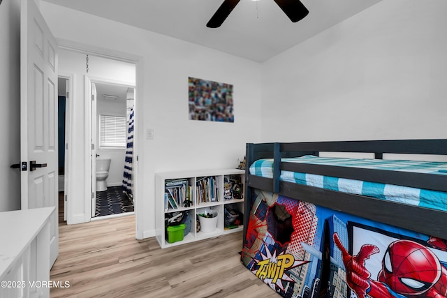 bedroom with a ceiling fan, wood finished floors, baseboards, and connected bathroom