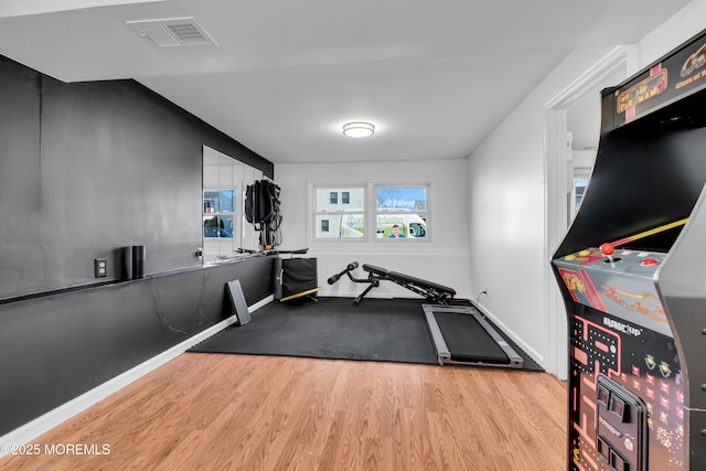 exercise area with wood finished floors, visible vents, and baseboards