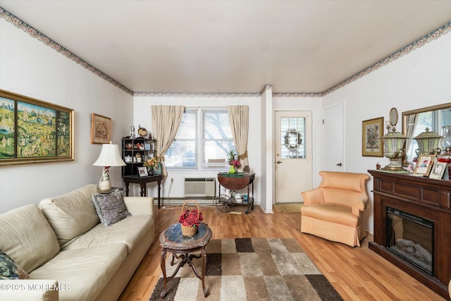 living room with a wall mounted AC and light hardwood / wood-style flooring