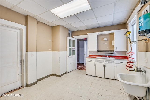 kitchen featuring sink, a paneled ceiling, and white cabinets