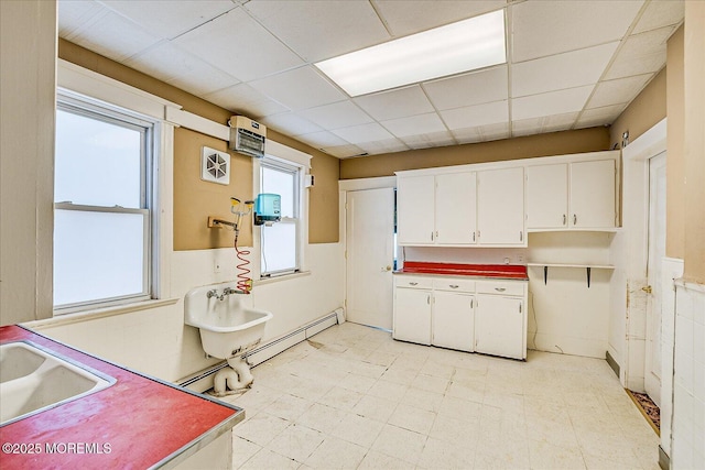 kitchen with white cabinetry, a paneled ceiling, sink, and a baseboard heating unit