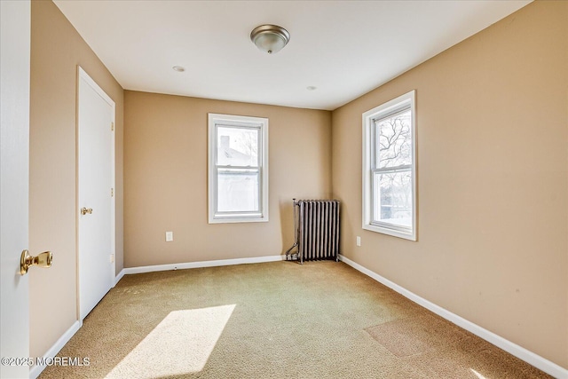 carpeted empty room featuring radiator heating unit and plenty of natural light