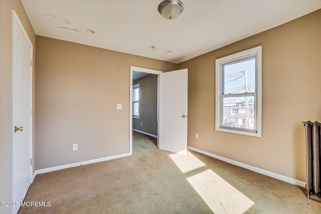 unfurnished bedroom featuring radiator and light colored carpet