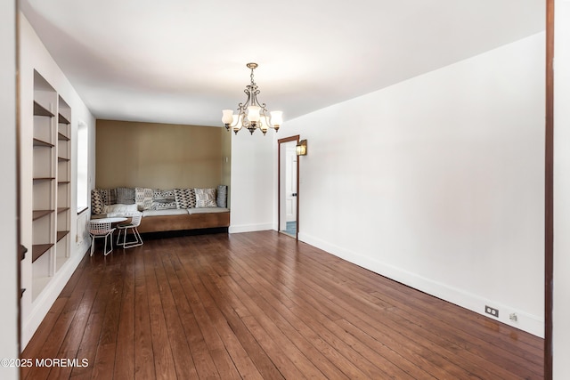 unfurnished room with dark hardwood / wood-style floors, an inviting chandelier, and built in shelves