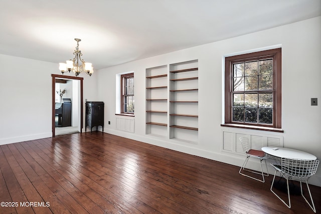 unfurnished living room featuring a notable chandelier and dark hardwood / wood-style floors