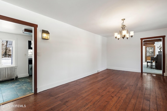 empty room with an AC wall unit, dark wood-type flooring, radiator heating unit, and an inviting chandelier