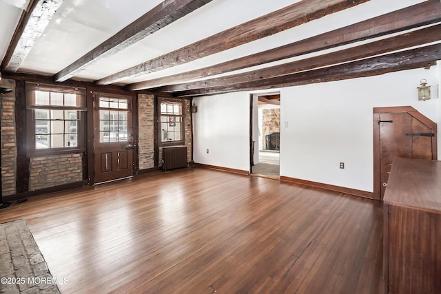 interior space featuring beamed ceiling, brick wall, radiator, and hardwood / wood-style floors