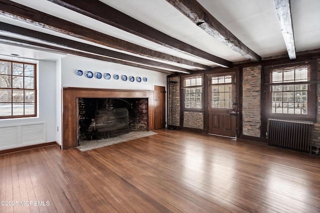 unfurnished living room with hardwood / wood-style flooring, a healthy amount of sunlight, radiator, and beam ceiling