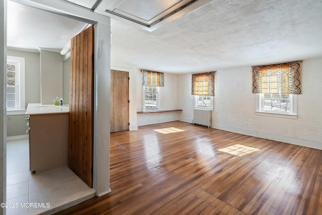 unfurnished living room with hardwood / wood-style flooring, radiator, and sink