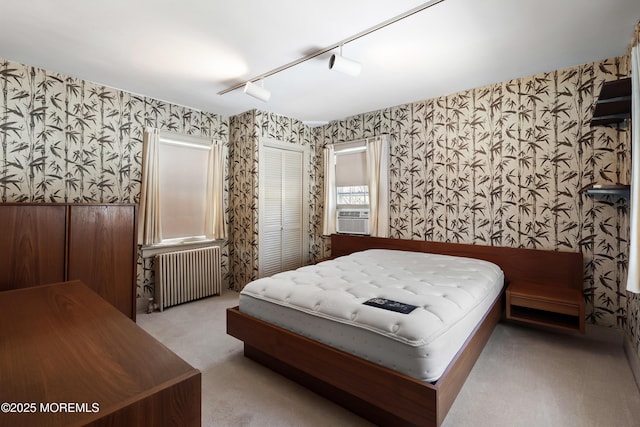 bedroom with rail lighting, radiator, a closet, cooling unit, and light colored carpet