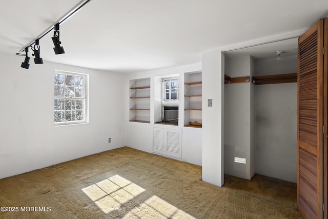 unfurnished bedroom with rail lighting, carpet, and a closet