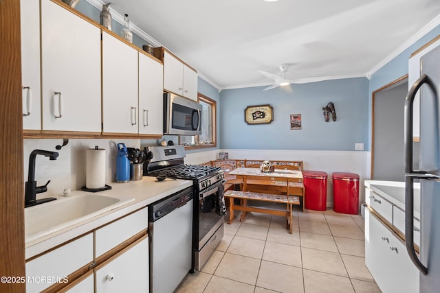 kitchen with white cabinetry, sink, ceiling fan, stainless steel appliances, and crown molding