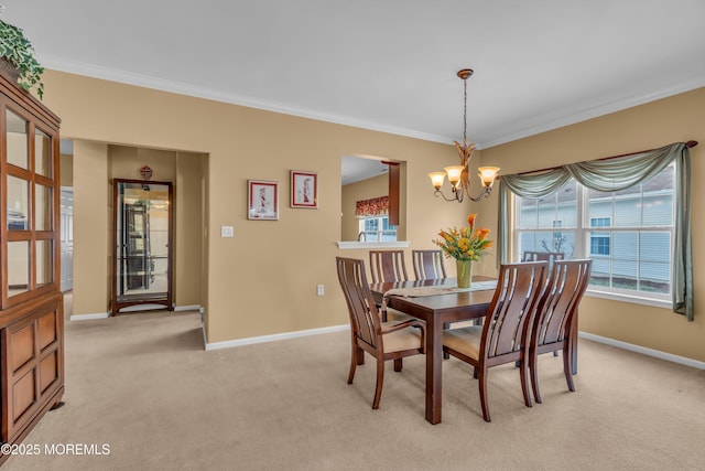 dining space with crown molding, light colored carpet, and a notable chandelier