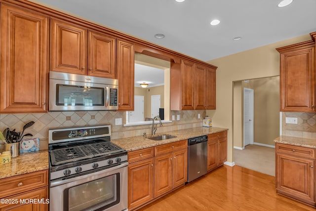 kitchen featuring sink, light hardwood / wood-style flooring, light stone countertops, and appliances with stainless steel finishes