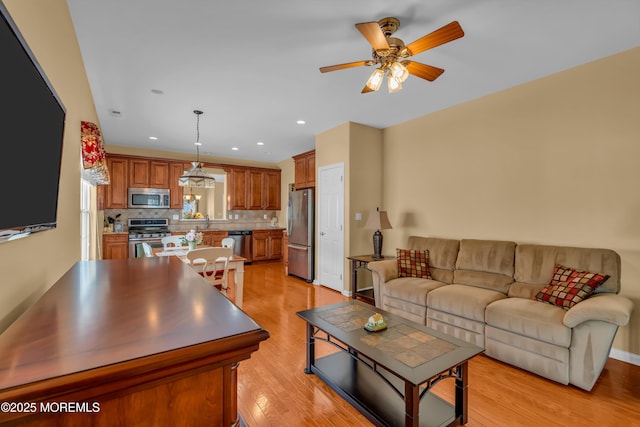 living room with sink, light hardwood / wood-style flooring, and ceiling fan