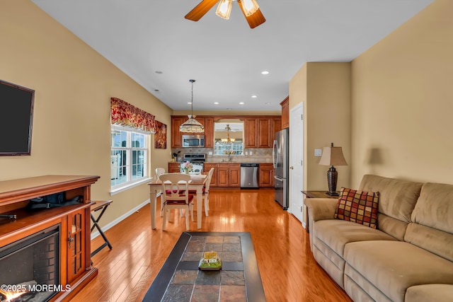 living room with sink, ceiling fan, and light hardwood / wood-style flooring