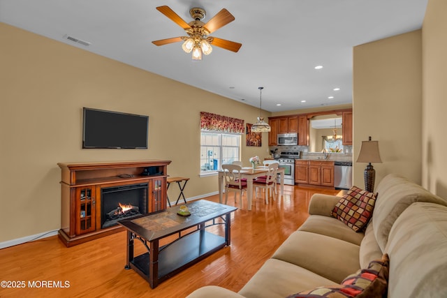 living room with sink, light hardwood / wood-style flooring, and ceiling fan