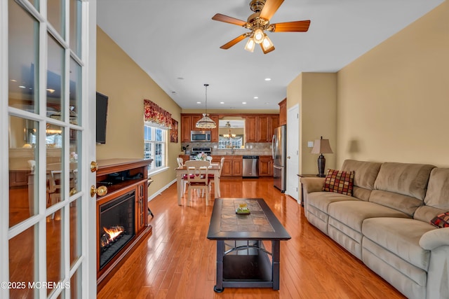 living room with light hardwood / wood-style flooring and ceiling fan