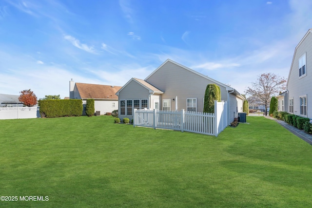 rear view of property with central AC unit and a yard