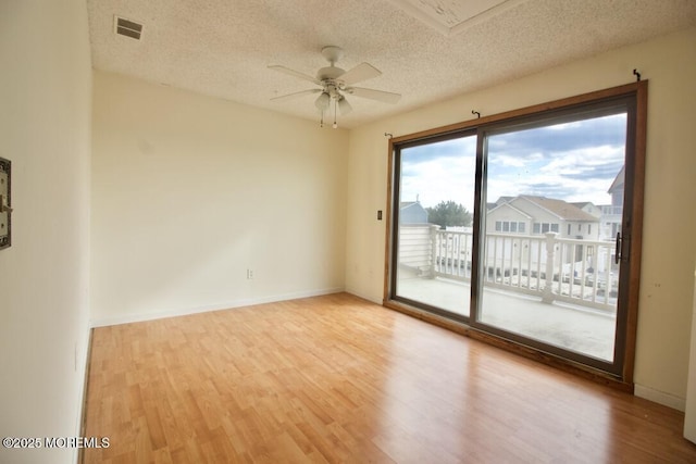 empty room with ceiling fan, light hardwood / wood-style flooring, and a textured ceiling