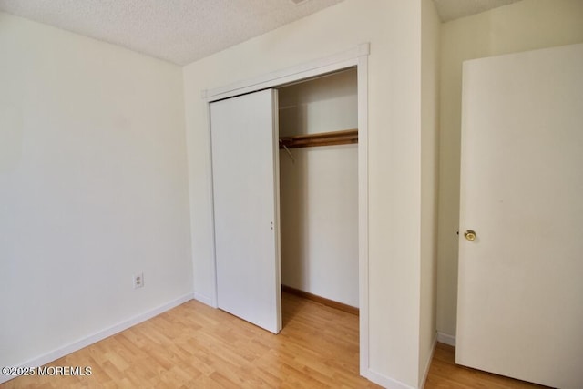 unfurnished bedroom with a closet, a textured ceiling, and light hardwood / wood-style flooring