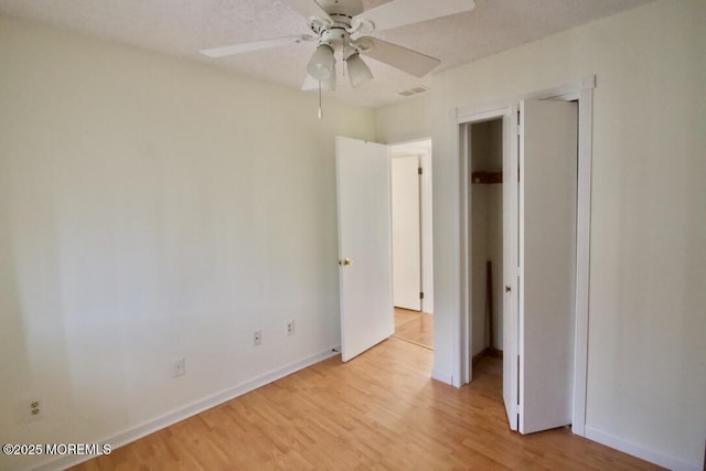 unfurnished bedroom featuring ceiling fan, a textured ceiling, and light wood-type flooring