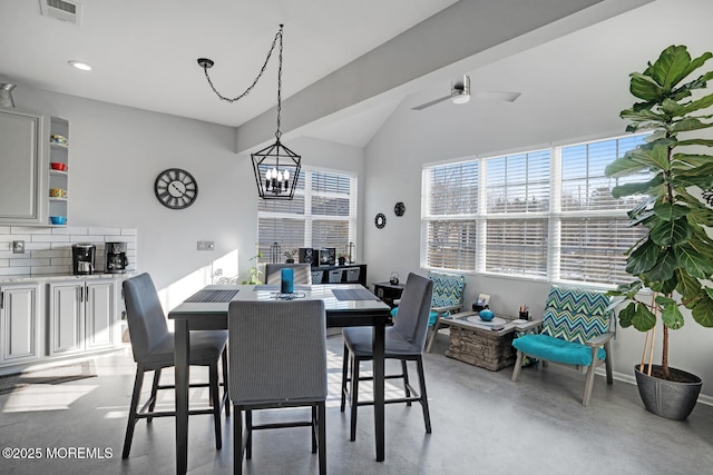 dining area featuring ceiling fan with notable chandelier and vaulted ceiling