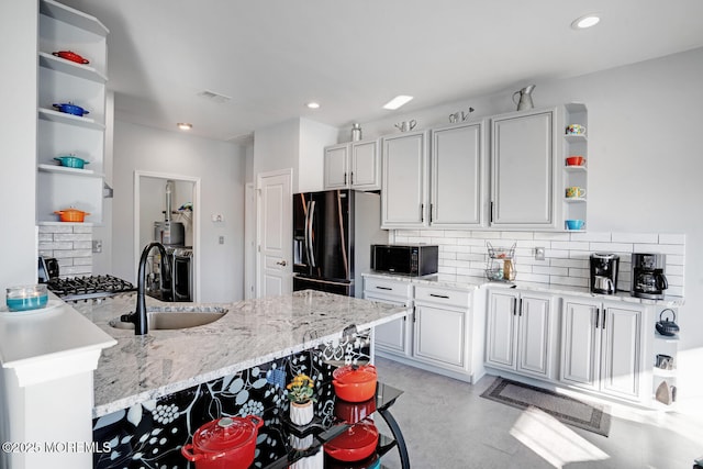 kitchen with refrigerator with ice dispenser, sink, light stone countertops, decorative backsplash, and kitchen peninsula