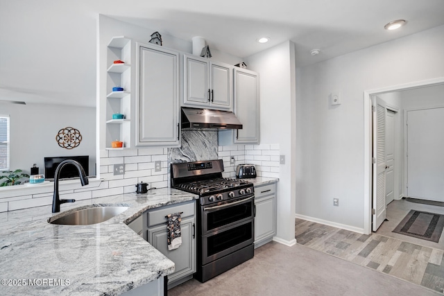 kitchen with gray cabinets, sink, range with two ovens, light stone countertops, and light hardwood / wood-style flooring