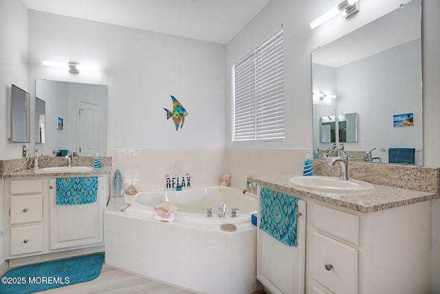 bathroom with vanity and tiled tub