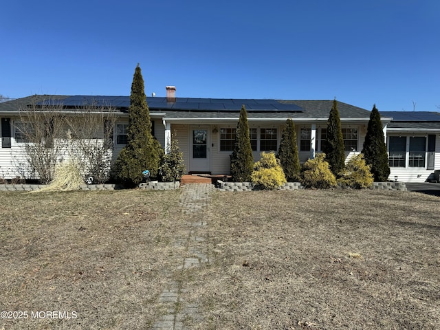 ranch-style house featuring roof mounted solar panels and a porch