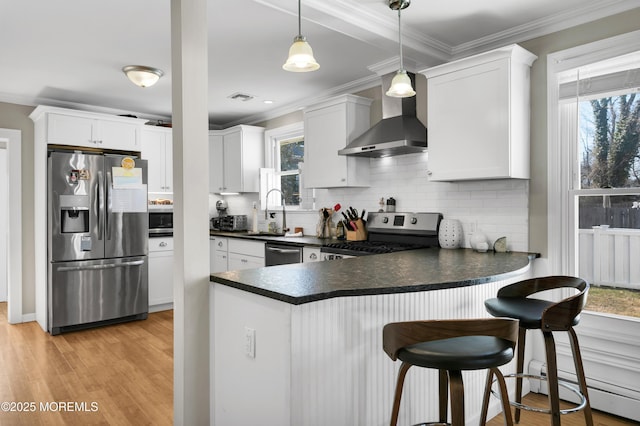 kitchen featuring a baseboard heating unit, stainless steel appliances, wall chimney range hood, decorative backsplash, and dark countertops